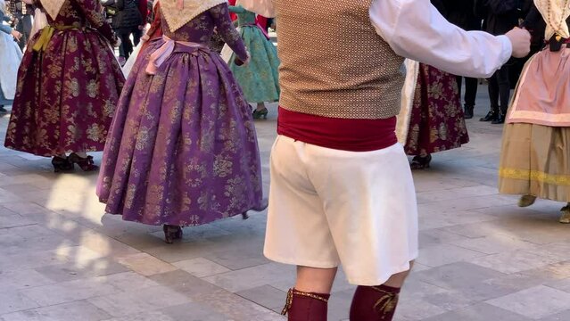 Group of people dressed in the traditional clothing of the festival of fallas performing a typical dance. Valencia, Spain