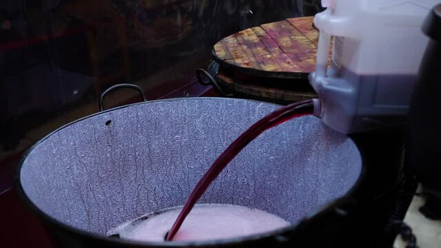 Pouring hot drink into a big container at a street market