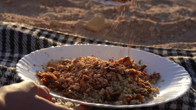 Pouring ground almonds over walnuts in the desert sunset