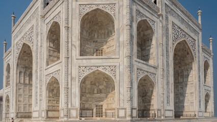 Fototapeta na wymiar Beautiful white marble Taj Mahal against the blue sky. Symmetrical mausoleum with arches, balconies, towers. The walls are inlaid with precious stones, ornaments. India. Agra