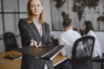 Woman in a suit holds a folder.