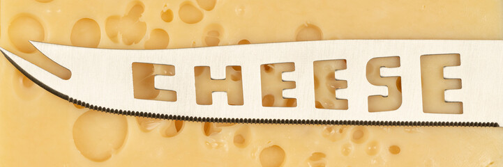 Knife with the inscription Cheese. Texture of Radomer cheese with close-up on a black background