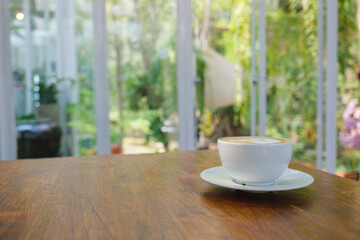 Closeup image of a cup of hot latte coffee on wooden table in cafe