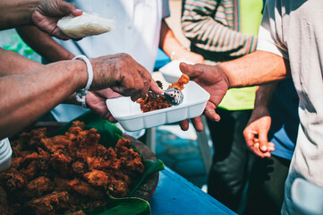 The concept of sharing food to hungry and starving people : Volunteers are handing out food to the poor.