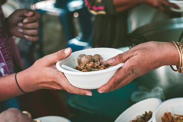 The concept of sharing food to hungry and starving people : Volunteers are handing out food to the poor.