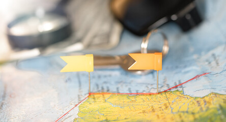 Magnifying glass with flag pins pinned on the map. Pushpin showing the location of a destination...