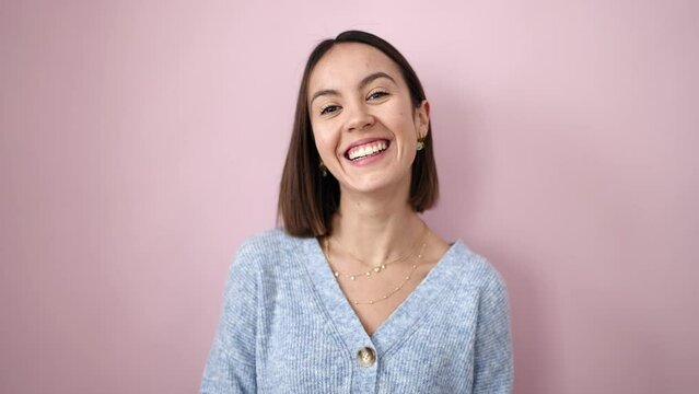Young beautiful hispanic woman smiling confident doing funny gesture with lips over isolated pink background