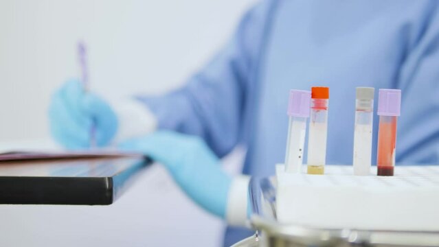Close-up of an Asian female doctor writing a list of blood test results.