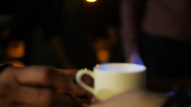 Galician queimada being served in a glass at night while it burns