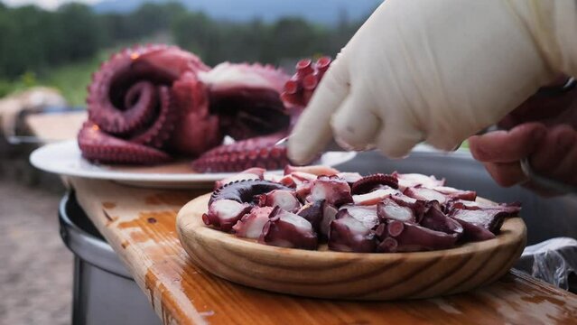Detail of the hands of a cook cutting an octopus leg with scissors to serve in "Pulpo a feira" typical Galician tapa