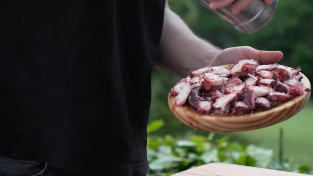 detail of a man preparing an octopus tapa, adding pepper and olive oil