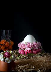 Easter eggs in a nest with flowers on a black background.