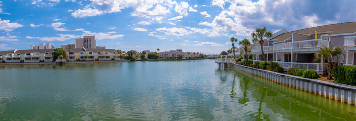 Fototapeta na wymiar Panoramic view of houses along a lake with brackish water in Destin Florida. The waterfront residential buildings have terraces overlooking a scenic nature landscape.