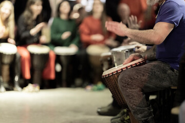 A large group of people playing the conga drums in a relaxed setting