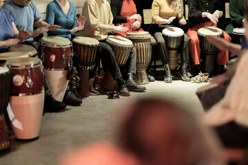 A large group of people playing the conga drums in a relaxed setting