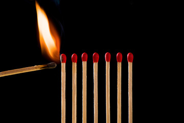 Light a match next to a row of unlit matches. Matchsticks burn