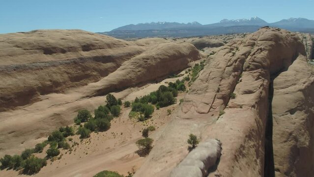 Aerial flying low over sandstone rock features on Fins n Things trail in Moab, Utah