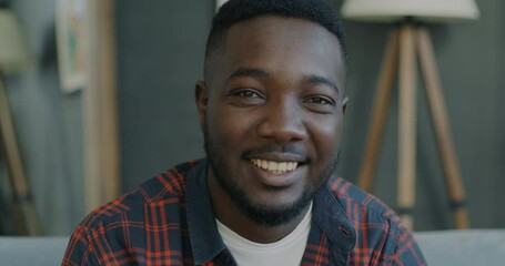 Slow motion portrait of young man in casual clothes smiling in apartment feeling happy at home. People and positive emotion concept.