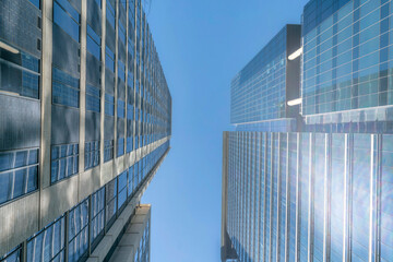 Fototapeta na wymiar Austin, Texas- High-rise buildings with a reflection of the sun on its glass walls. Two modern building structures with glass walls and a blue sky background.