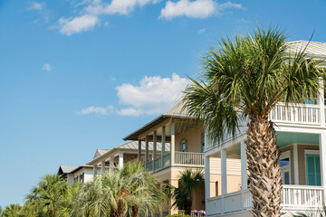 Row of houses with balconies with palm trees view at the front in Destin, Florida. There are palm trees at the front of the houses under the sky.