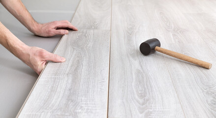 Man lays laminate on the floor, butt-joining the boards. Repair and decoration of premises. Modern flooring. Plank connection. Soft focus. Close-up.