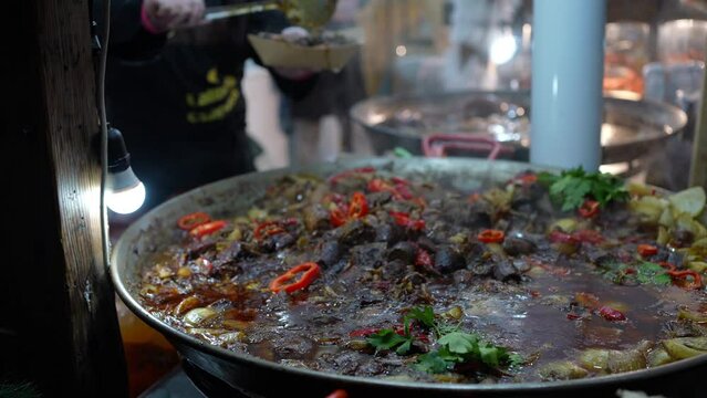 Cooking street food vegetables and meat in big pot