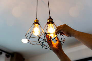 Decorative antique edison style filament light bulbs hanging. An electrician is installing...