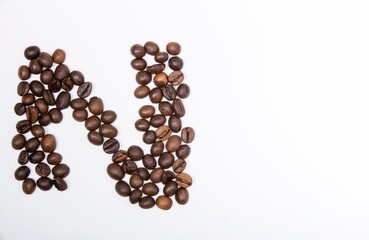 N is a capital letter of the English alphabet made up of natural roasted coffee beans that lie on a white background.