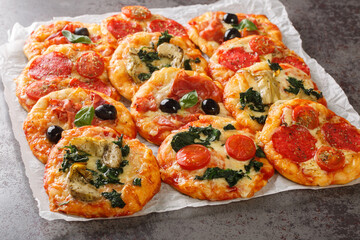 Italian Pizzette Mini Pizza Bites With Assorted Toppings close-up on parchment on the table. Horizontal