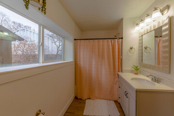 White bathroom interior with sliding window across the vanity sink with framed mirror. Bathroom...