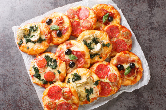 Pizzette Italian mini pizzas or pizza bites close-up on parchment on the table. Horizontal top view from above