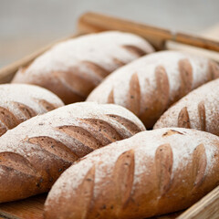 Freshly baked loaves with whole grain flour seeds on wooden tray. Fresh bakery. Healthy diet. Bakery. Close-up. Side view. Soft focus. 
