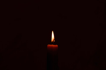 One light candle burning brightly in the dark background.Copy space.