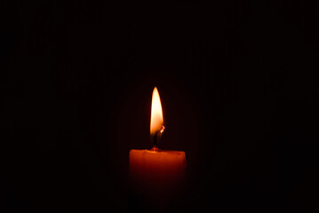 Old lighting a candle in the dark.Close up single candle light and flame on black background. Melted Wax Candle light border design. Burning at Night, Darkness.Candlelight.Copy space.