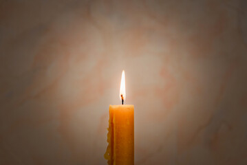 Candle light for spirituality ceremony against grey blurred background.Hot wax drips from the candle.Copy space.