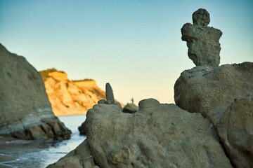 View of a beach of Corfu in Greece along cliffs in the foreground rocks with a stone figure in the...