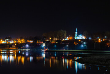 Fototapeta na wymiar Telsiai town,water night lake in Lithuania. Nice view winter of colorful houses on coast of frozen Lake.Nice winter night.Town colorful light reflections on water.Long exposure.