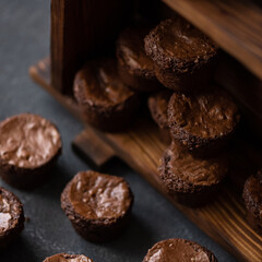 Chocolate muffins. Lots of little desserts. Chocolate pastry. Cupcakes on wooden shelf. Dark background. Top view. Soft focus. 