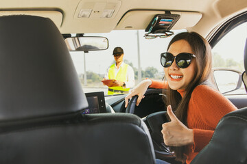 Beautiful young asian amateur girl in sunglasses showing thumbs up ready for practical driving lessons taught by expert driving school instructors drive safely on the roads according to traffic rules.