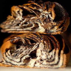 Babka with chocolate filling. Twisted sweet traditional Jewish pastries. Puff twisted pastries. Close-up. Cross-sectional side view. Soft focus. Dark background. 