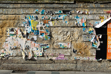 The stone wall covered with scraps of announcements.