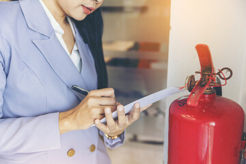 woman worker inspection chemical Fire extinguisher and fire hose. writing on monthly check...