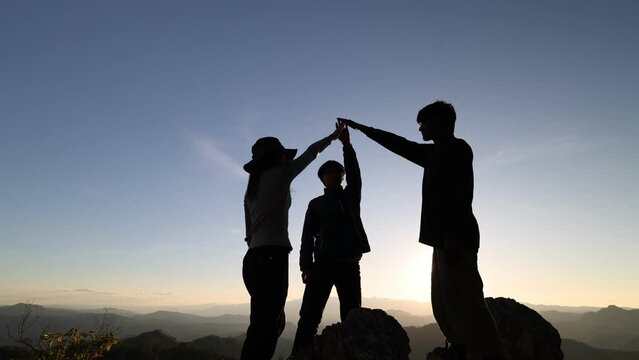 silhouette of mountain climbers stretching out their hands climb to the top of the mountain concept of teamwork, victory and success Tourists have met with success. 4K slow motion.