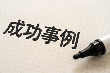 成功事例と書かれたノートとマーカー
