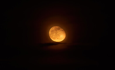 Orange full moon. High-resolution picture of the moon by telescope, with the moon illuminated at 90%