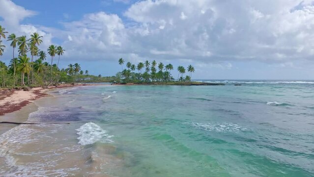 Drone flying over turquoise waters of Los Coquitos beach, Cabrera in Dominican Republic. Aerial forward