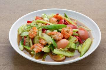 close up of thai style spicy cucumber salad in a ceramic dish on wooden table. asian homemade food concept.