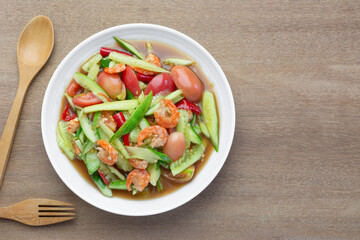 top view of thai style spicy cucumber salad in a ceramic dish on wooden table. asian homemade food concept.