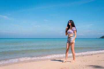 Summer lifestyle portrait of young girl enjoying on the tropical island. In the background the sea. Wearing Crop tops and shorts relaxed, Straight long hair.summer travel concept.