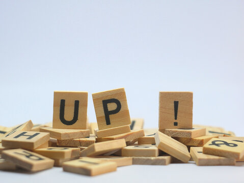Word UP ! on a pile of wooden letters, on a white background.